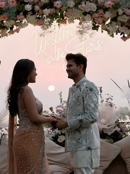 We work to capture the full scale of your event, including the stunning decor. This shot frames the couple against a beautiful floral arch and a "Written in the Stars" neon sign, preserving the ambiance of their special day.