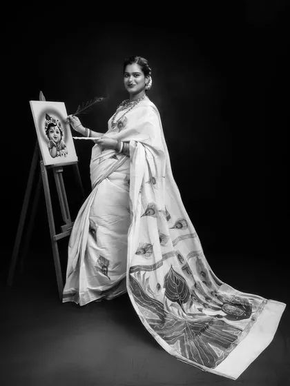 This is the black and white version of the artistic maternity portrait. The monochromatic tones emphasize the form, emotion, and the beautiful contrast between the mother's flowing saree and the act of painting, creating a classic and dramatic feel.