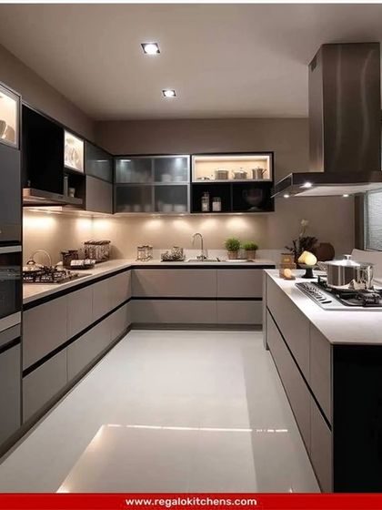 This U-shaped kitchen offers a professional cooking environment with two separate hobs and ample counter space. The two-tone grey and black cabinets, along with glass-front storage, create a sleek and organized look.