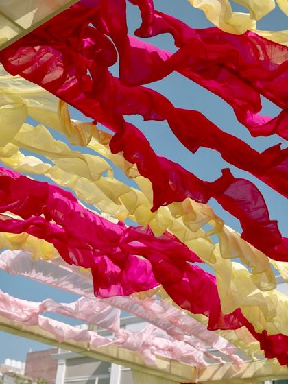 A view of the sky through the colorful ruffled fabric ceiling, a simple yet effective way to add color and texture to an outdoor event.