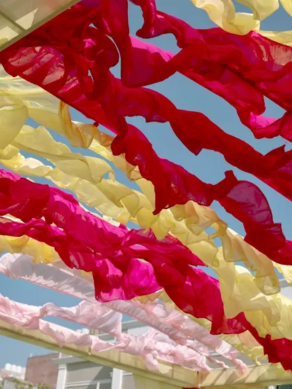 A view of the sky through the colorful ruffled fabric ceiling, a simple yet effective way to add color and texture to an outdoor event.