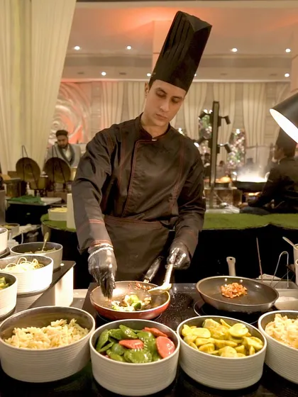 Our chef at a live pasta bar, surrounded by a variety of fresh ingredients, ready to customize a perfect plate of pasta for each guest.