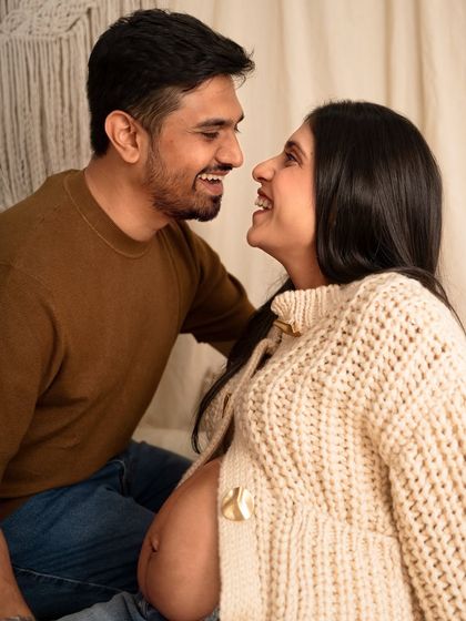 Pure connection captured in a candid moment. This couple shares a laugh during their cozy, relaxed maternity photoshoot, showcasing their genuine happiness.