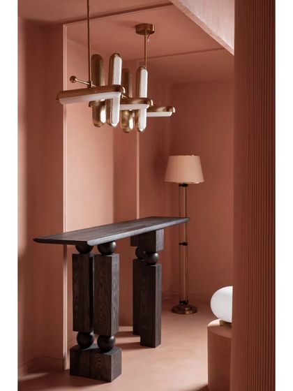 This view highlights a modern, artistic chandelier paired with a bold, geometric console table. The composition shows our approach to balancing sculptural furniture with statement lighting fixtures.