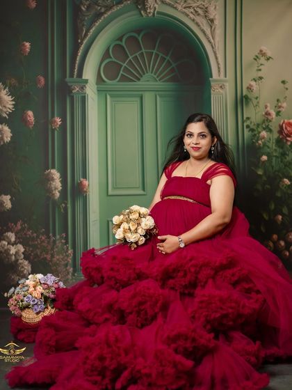 A seated portrait holding a bouquet of flowers, this mother-to-be looks like a queen on her throne in this incredible red gown.