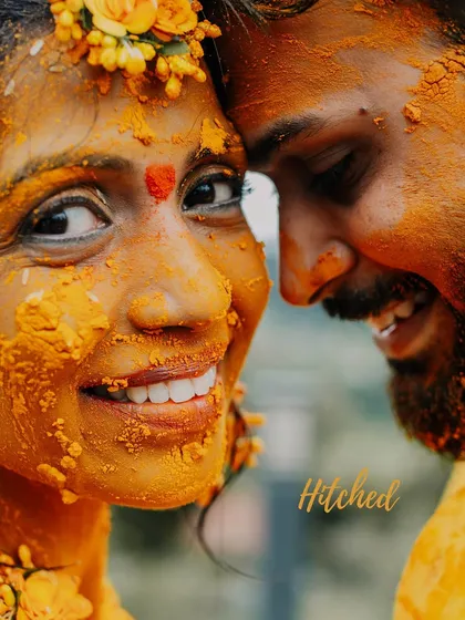 A close-up of a bride's joyful, turmeric-covered face. Her smile says it all. This is a moment of pure, uninhibited happiness, a beautiful start to the wedding celebrations.