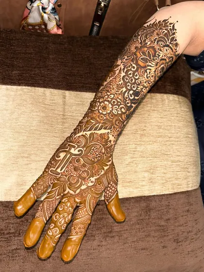 A full-arm design with the initial 'T' prominently featured on the palm, surrounded by a sea of intricate patterns.