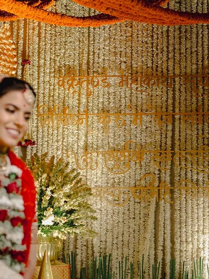 A close-up showing the backdrop of tuberose strings with sacred verses woven into it with marigolds, a truly bespoke detail.