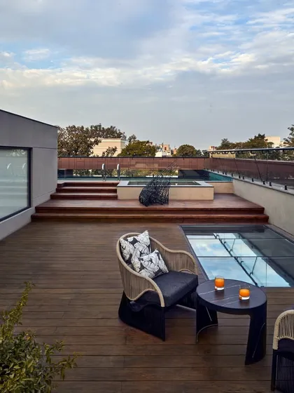 The terrace at the Baid Residence, offering breathtaking views of the Jahanpanah forest. The space is designed for outdoor relaxation, with comfortable seating and a patterned granite floor.