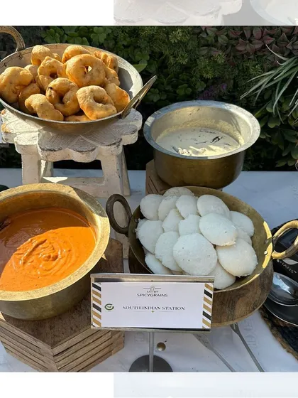 A close-up of our South Indian station, highlighting the soft, pillowy idlis and crispy golden-brown vadas, ready to be enjoyed with our homemade chutneys.