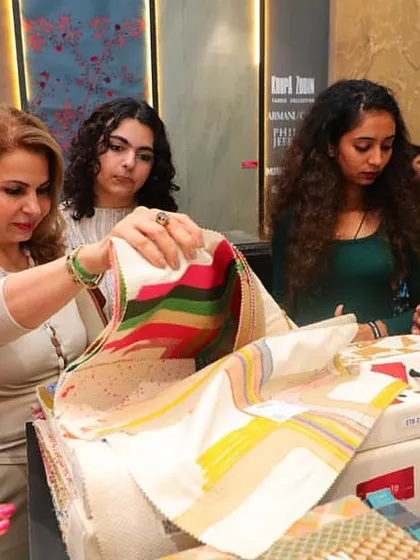 A client explores a vibrant, striped fabric sample at our booth during the Ajio Luxe Weekend. This moment captures the excitement of the design process, where clients can see and feel the quality of our collections firsthand.
