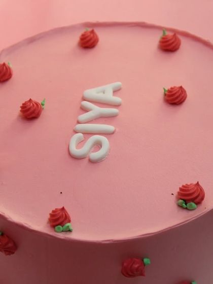 A close-up of the naming ceremony cake, highlighting the neat lettering and delicate rose details.