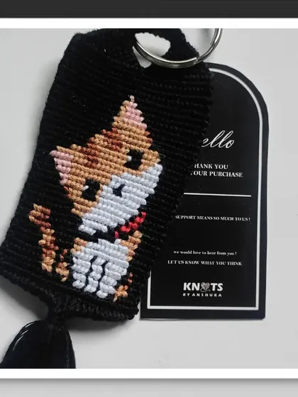 This knotted keychain features a calico cat design, perfect for all the cat parents out there. The little tassel at the bottom adds a nice finishing touch.