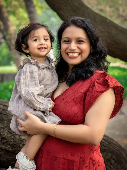 A mother and daughter's bright smiles light up this outdoor portrait. The natural green background makes their happy expressions pop even more.