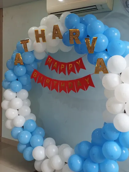A close-up of the blue and white balloon ring, showing the detail of the balloon arrangement and the gold foil name letters.