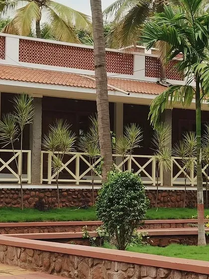We designed this 8000 sqft farmhouse, "Grid in the Grove," to coexist with nature. The structure embraces the existing coconut grove, using rustic materials like terracotta and unfinished granite to create a timeless retreat inspired by Hampi's architectural splendor.