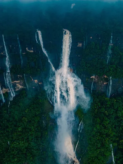 The majestic Nohkalikai Falls in Meghalaya, India's tallest plunge waterfall, seen from the air. The mist and spray create an ethereal, dreamlike atmosphere.