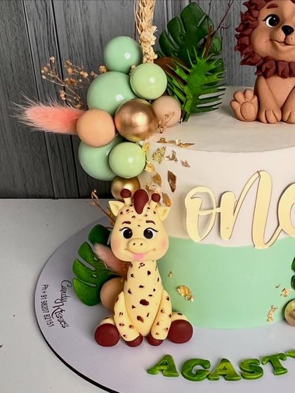 A close-up of the cute giraffe figurine and the balloon-like spheres on the jungle-themed cake.