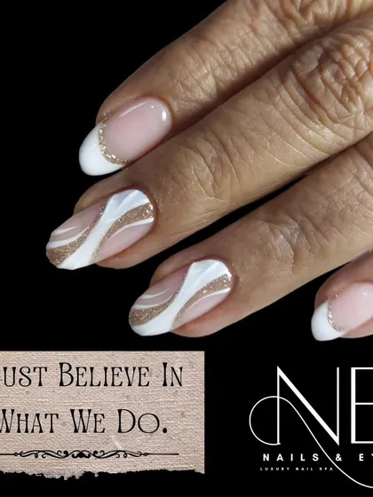A simple and elegant design on short, natural nails. This look features a modern French tip and an abstract accent nail with flowing white and gold glitter lines.