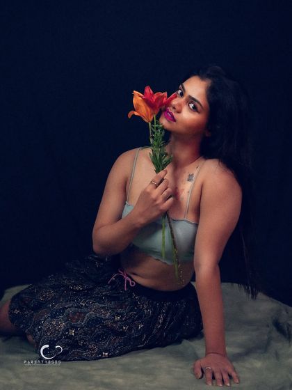A full-body shot that showcases the contrast between the delicate flowers and her strong, confident pose.