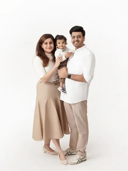 A classic and elegant full-length studio portrait of a mother, father, and their young son, coordinated in neutral-toned outfits.