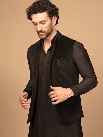 A stylish shot of the black velvet Nehru jacket, layered over a tonal kurta. This ensemble is all about texture and understated luxury, creating a look that is both modern and timeless.
