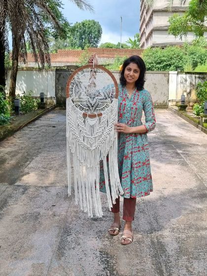 Holding our custom plywood-based macrame wall hanging. The intricate patterns and natural wood finish create a harmonious blend of rustic charm and modern elegance.
