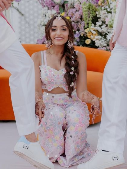 A playful moment from a wedding ceremony. We designed this bride's pastel-hued floral co-ord set, which perfectly complements the groom's and groomsmen's white outfits.