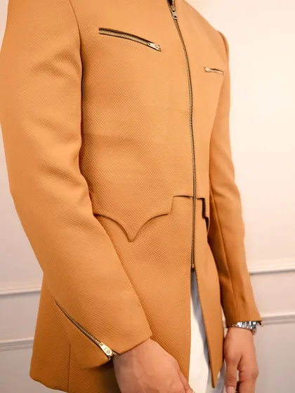 A detailed shot of the tan bandhgala's unique cut and zipper detailing on the chest and cuffs, showcasing the functional and stylish elements I incorporate.