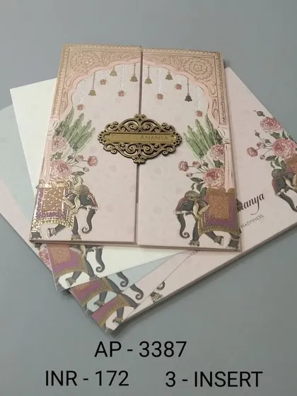 This gate-fold invitation in a soft pink hue is decorated with royal elephants and floral designs. A wooden nameplate holds the card closed, adding a rustic and personal touch.