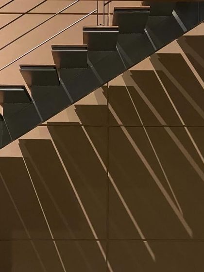 A minimalist and modern staircase design, where the sharp lines of the steps and railing create a dynamic play of diagonal shadows. This image highlights our focus on intentional design, where even simple elements are elevated through light and form.