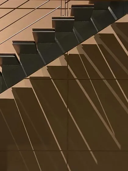 A minimalist and modern staircase design, where the sharp lines of the steps and railing create a dynamic play of diagonal shadows. This image highlights our focus on intentional design, where even simple elements are elevated through light and form.