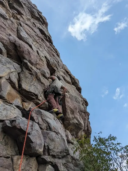 A climber makes her way up a textured rock face, with her rope and belayer providing security from below. This is what sport climbing is all about.