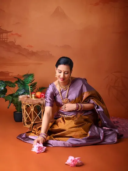 A serene solo portrait of the mom-to-be in her saree. She is seated on the floor against a painted landscape, creating a peaceful and artistic composition.