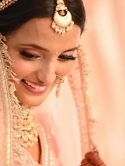 A shy, beautiful smile from bride Mokshi. Her simple makeup and pastel lehenga create a look of pure, understated elegance.