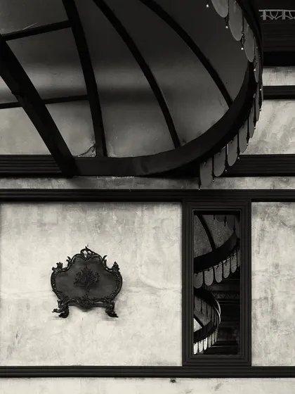 An artistic detail shot showing the reflection of the bar's canopy lights in a window, juxtaposed with a decorative wall plaque. This highlights the layers of detail in the design.