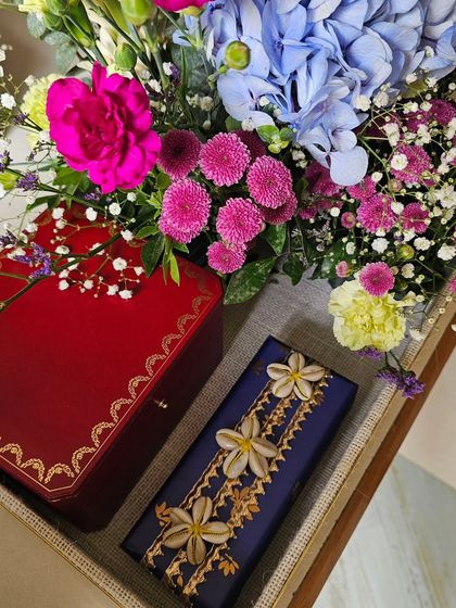 Wedding season is in full swing, and I'm loving the beautiful chaos. This arrangement features a luxurious red box paired with a gift wrapped in deep blue and adorned with delicate shell flowers.