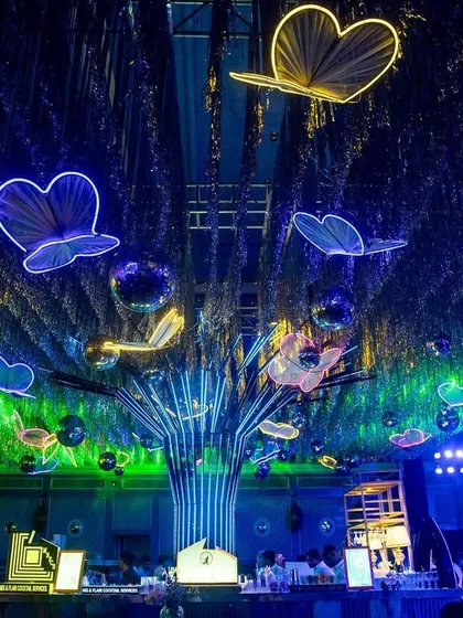 A ceiling full of neon butterflies and disco balls for a high-energy cocktail party. This design transformed the ballroom into a magical, glowing forest, perfect for a night of dancing.