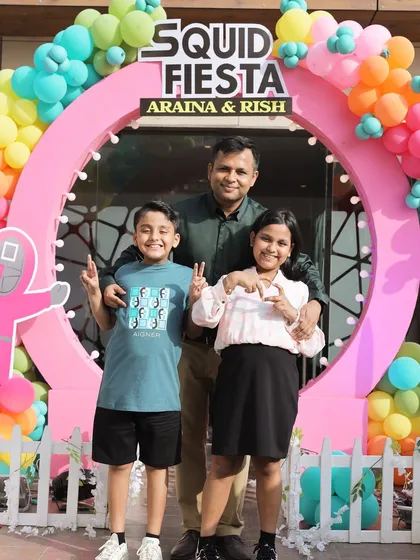A happy family moment at the 'Squid Fiesta' birthday party. The vibrant entrance arch serves as a fantastic photo opportunity for guests and the hosts.