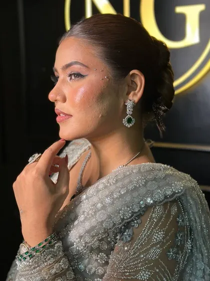 A side profile showcasing the flawless base and the clean lines of the hairstyle. The highlighter catches the light beautifully, emphasizing the cheekbones and adding a radiant finish.
