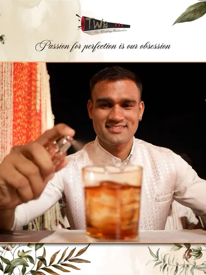 A bartender sprays an aromatic mist over a finished cocktail. This final touch adds a subtle layer of scent, enhancing the overall sensory experience of the drink.