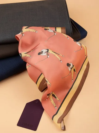 The golfer-themed pocket square styled with folded suiting fabrics, suggesting pairings and context.