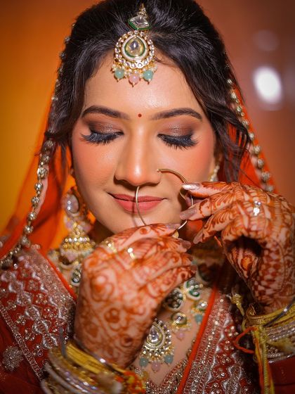 A close-up of a Punjabi bride, focusing on her henna and the delicate nath.