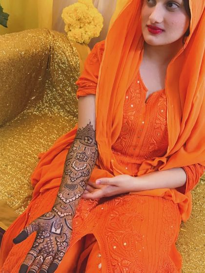 The beautiful bride Noora in her orange outfit, showing off her intricate Pakistani henna design.