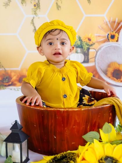 This little baby in a yellow dress looks curious and cute in our sunflower-themed set. We capture these candid expressions that make each photo special.