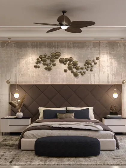 Texture and lighting are key to this bedroom design. A concrete-finish accent wall is paired with a quilted headboard and artistic metal wall decor, while hanging pendant lights provide warm, focused illumination for a cozy atmosphere.