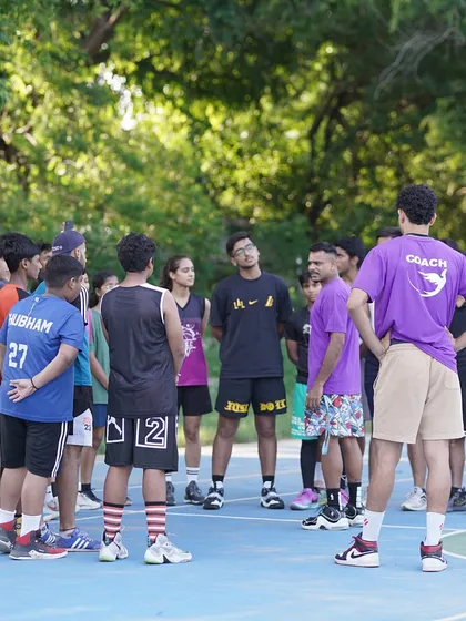 A group of players huddles around a coach during our basketball skills workshop in Khan Market, a great example of our community outreach.