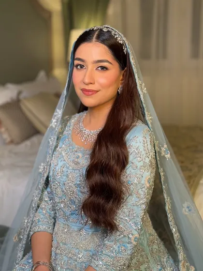 A close-up portrait with the veil. The makeup is soft and ethereal, with a focus on her bright eyes and luminous skin.