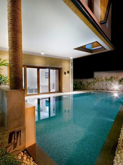 This residential pool is designed for evening enjoyment, with underwater lights and strategically placed landscape lighting. The covered patio area provides a comfortable space to relax by the water, day or night.