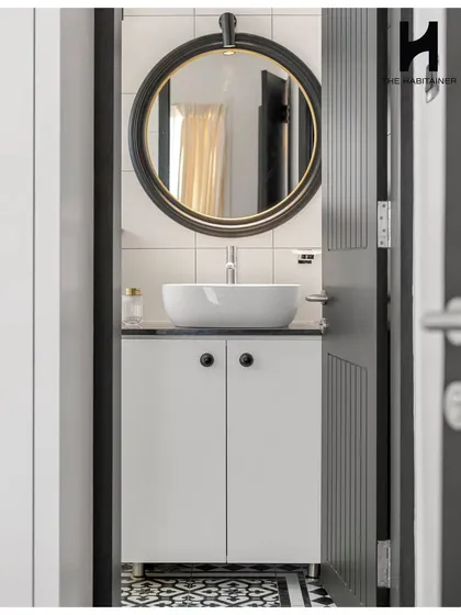 The chic washroom in the same home features bold black-and-white patterned floor tiles. A modern vessel sink sits atop a simple vanity, with a large round mirror and elegant lighting completing the look.